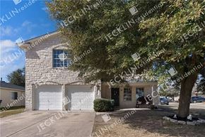 Hutto house for rent - a stone house with two garage doors and a tree