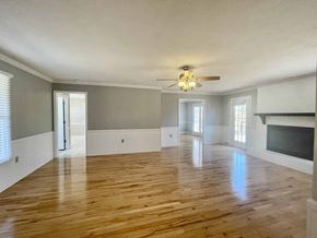 Greer house for rent - A spacious room with wooden floors and a fireplace.