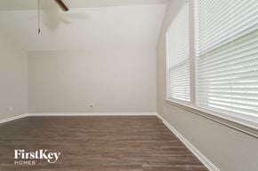 Little Elm house for rent - the bedroom of a home with a large window and wood flooring