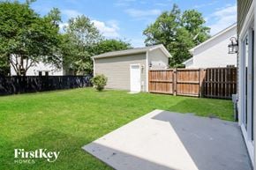 Johns Island house for rent - A backyard with a concrete walkway, a fence, and a small tree.