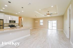 Lehigh Acres house for rent - an empty kitchen and living room with a ceiling fan