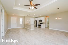 Lehigh Acres house for rent - an empty living room and kitchen with a ceiling fan