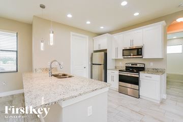 Lehigh Acres house for rent - a white kitchen with stainless steel appliances and a marble counter top