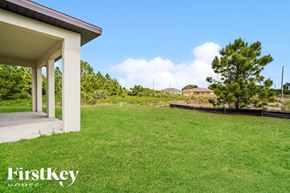 Lehigh Acres house for rent - a backyard with green grass and a white house