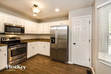 Summerville house for rent - A kitchen with a stainless steel refrigerator and white cabinets.