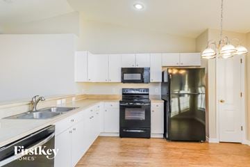 Lehigh Acres house for rent - a white kitchen with stainless steel appliances and white cabinets