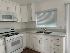 Whittier apartment for rent - A white kitchen with a stove, microwave, and sink.