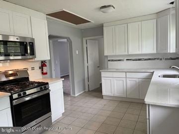 Ocean Township house for rent - A kitchen with white cabinets and a black stove top.