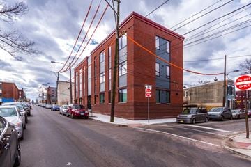 Philadelphia apartment for rent - a red brick building on the corner of a street with parked cars