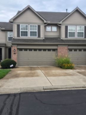 Mason house for rent - A house with a grey garage door and a brick pillar.