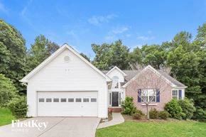 Dacula house for rent - A white house with a garage is surrounded by greenery.