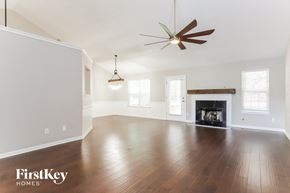 Dacula house for rent - A spacious living room with a fireplace and a ceiling fan.