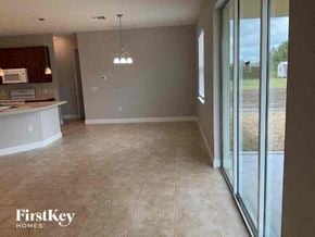 Lehigh Acres house for rent - an empty kitchen and living room with sliding glass doors