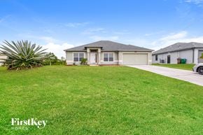 Cape Coral house for rent - a house with a lawn and a car in front of it