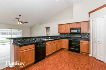 Cape Coral house for rent - a kitchen with black appliances and wooden cabinets
