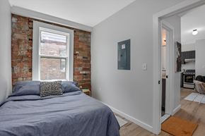 Detroit apartment for rent - a bedroom with a bed and a brick wall