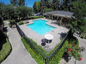 Modesto apartment for rent - A pool surrounded by a black fence and greenery.