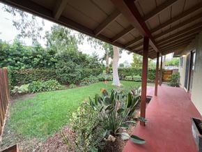 Fullerton apartment for rent - A red covered walkway leads to a building with a garden on the other side.