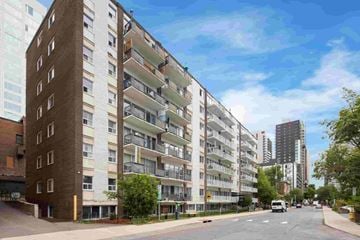 Ottawa apartment for rent - A street view of a residential area with apartment buildings on the left and a parked car on the road.