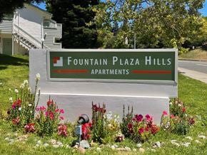 Vallejo apartment for rent - A sign for Fountain Plaza Hills Apartments is surrounded by flowers.
