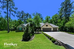 Dayton house for rent - A house with a driveway and a garage is surrounded by trees.