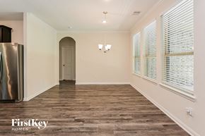 Dayton house for rent - A spacious room with wooden flooring and a refrigerator on the left side.