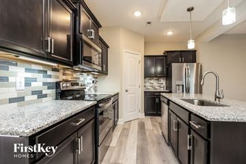 Clarksville house for rent - a kitchen with black cabinets and granite counter tops and a sink
