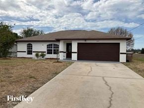 Cape Coral house for rent - a white house with a driveway and a garage door