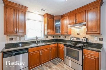 Lilburn house for rent - A kitchen with wooden cabinets and a stove top oven.