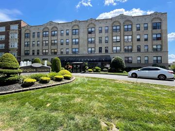 East Orange apartment for rent - A white car is parked in front of a large building.