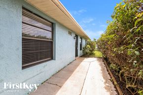Lehigh Acres house for rent - a side view of a blue house with a sidewalk and bushes