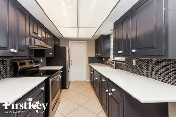 Lehigh Acres house for rent - a kitchen with black cabinets and white counters and a door