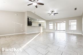 North Port house for rent - an empty living room with a kitchen and ceiling fans