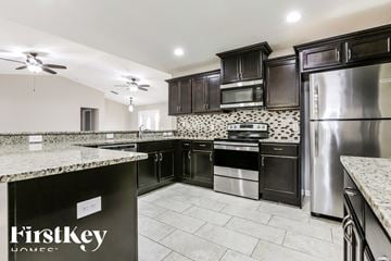 North Port house for rent - a kitchen with black cabinets and stainless steel appliances