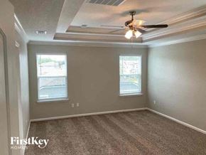 Jacksonville house for rent - an empty bedroom with a ceiling fan and two windows