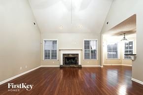 Fayetteville house for rent - A large empty room with a fireplace and wooden floors.