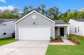 Summerville house for rent - A grey house with a white garage door and a small garden in front.