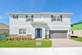 Howey In The Hills house for rent - A white two-story house with a garage door and a stone wall.