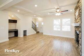 Clarksville house for rent - an empty living room with a fireplace and a ceiling fan
