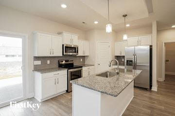 Clarksville house for rent - a kitchen with white cabinets and granite counter tops