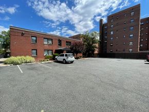 East Orange apartment for rent - A parking lot with a white car and a building in the background.