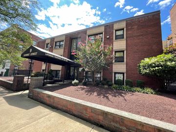 East Orange apartment for rent - The image shows a building with a sign that reads "9 Summit Street" and a brick wall in front of it.