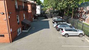 Irvington apartment for rent - A parking lot with cars parked in front of a brick building.