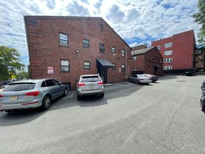 East Orange apartment for rent - A parking lot with cars and a brick building.