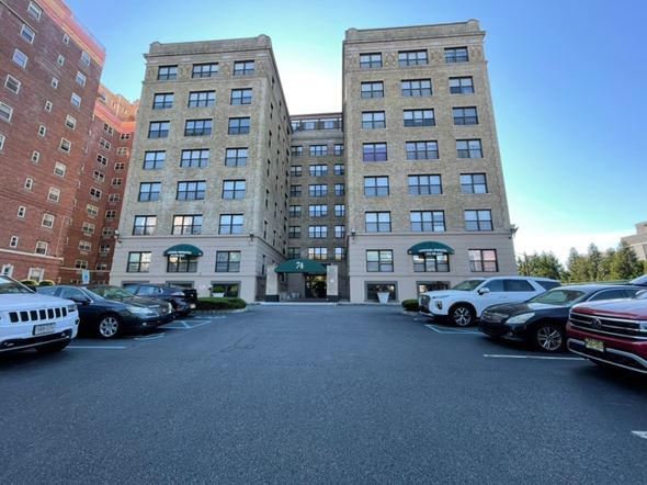 East Orange apartment for rent - A parking lot in front of a multi-story building with cars parked.