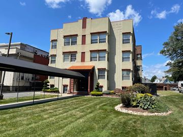 East Orange apartment for rent - A large building with a red awning and a landscaped front yard.