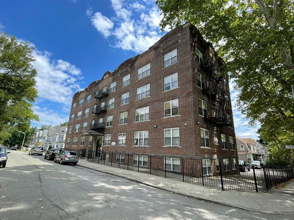 East Orange apartment for rent - A tall brick building with a black fence in front of it.
