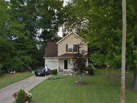 Warren house for rent - A house with a white door and windows is surrounded by greenery.