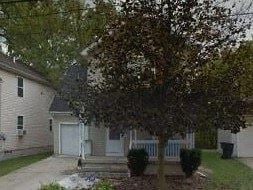 Warren house for rent - A house with a white garage door is surrounded by a small garden.