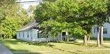 Warren house for rent - A white house with a porch is surrounded by trees.